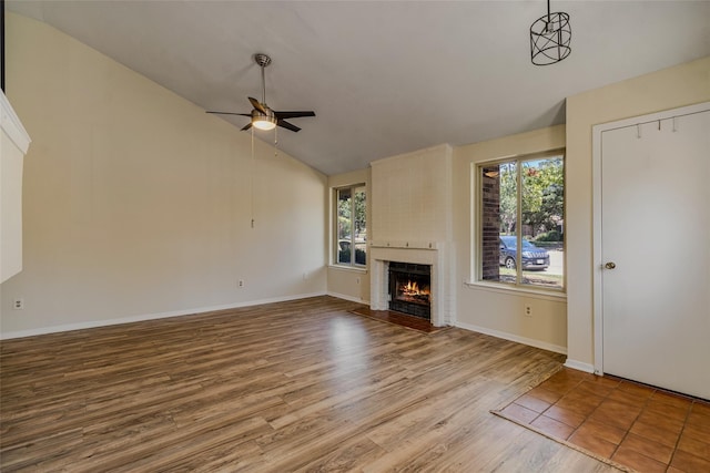 unfurnished living room featuring wood finished floors, baseboards, a ceiling fan, a fireplace, and vaulted ceiling