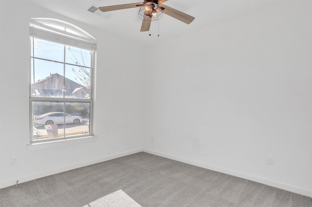 carpeted spare room featuring visible vents, baseboards, and a ceiling fan