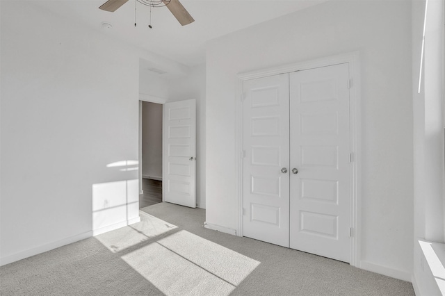 unfurnished bedroom featuring a closet, light carpet, baseboards, and ceiling fan