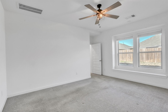 carpeted spare room with visible vents, ceiling fan, and baseboards