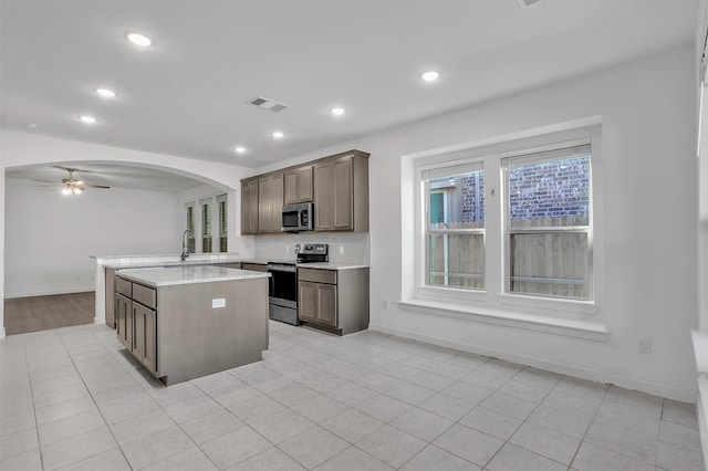 kitchen with visible vents, a ceiling fan, a sink, stainless steel appliances, and arched walkways