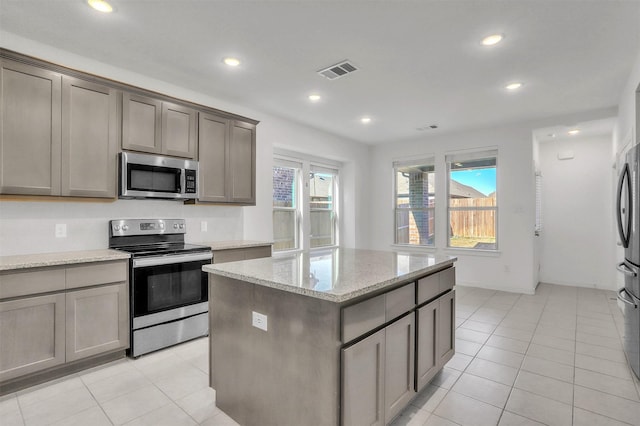 3917 Spencer Ln, Heartland, TX 75126 - kitchen with stainless steel appliances, a kitchen island, light tile patterned floors, recessed lighting, and light stone counters