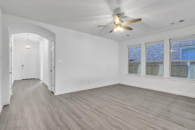 unfurnished room with visible vents, arched walkways, baseboards, and wood finished floors