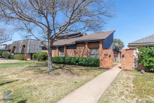 view of front of property with brick siding, a front lawn, and a gate