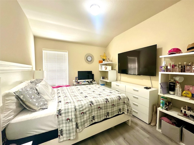 bedroom with vaulted ceiling and wood finished floors