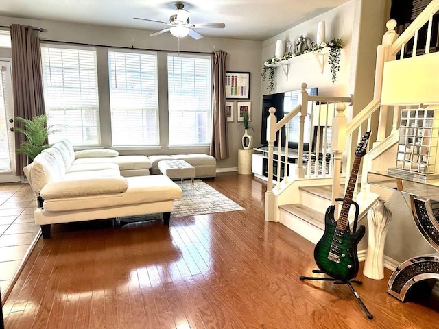 living room featuring baseboards, stairs, ceiling fan, and hardwood / wood-style floors