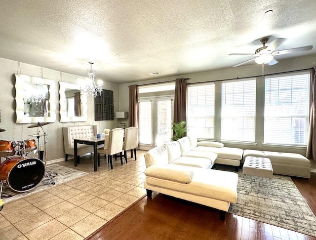 living area with visible vents, ceiling fan with notable chandelier, a textured ceiling, and wood finished floors