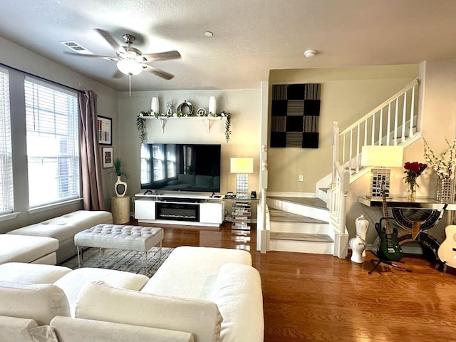 living room with visible vents, stairway, wood finished floors, a textured ceiling, and a ceiling fan