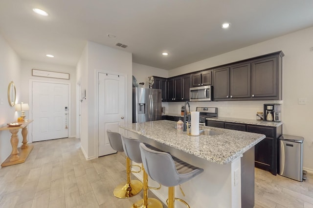 kitchen featuring visible vents, light wood-style flooring, stainless steel appliances, and light stone countertops