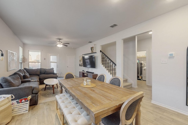 dining area featuring visible vents, baseboards, stairs, and light wood finished floors