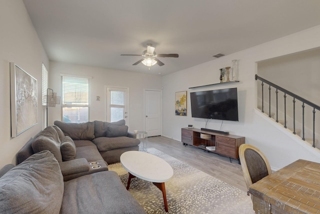 living room featuring visible vents, stairs, ceiling fan, and wood finished floors