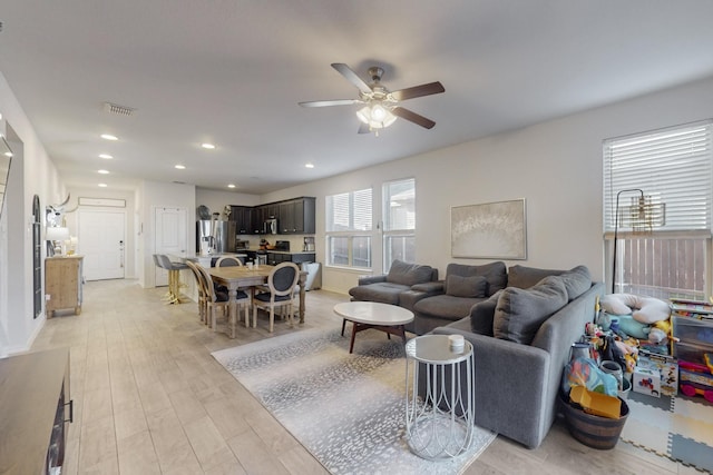 living room with a ceiling fan, recessed lighting, visible vents, and light wood finished floors