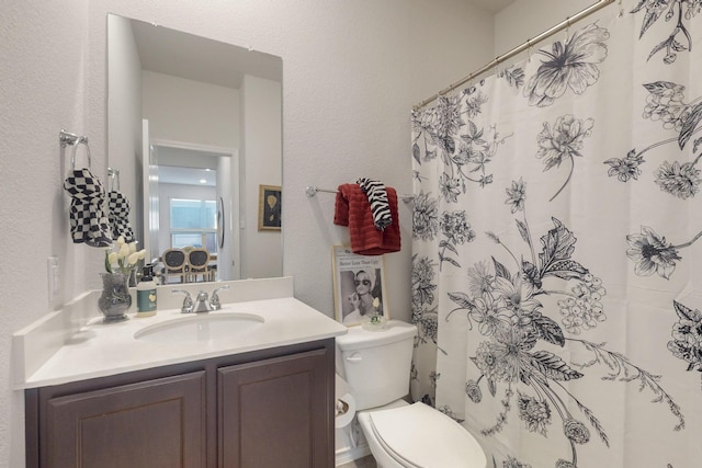 full bath with a shower with shower curtain, toilet, vanity, and a textured wall