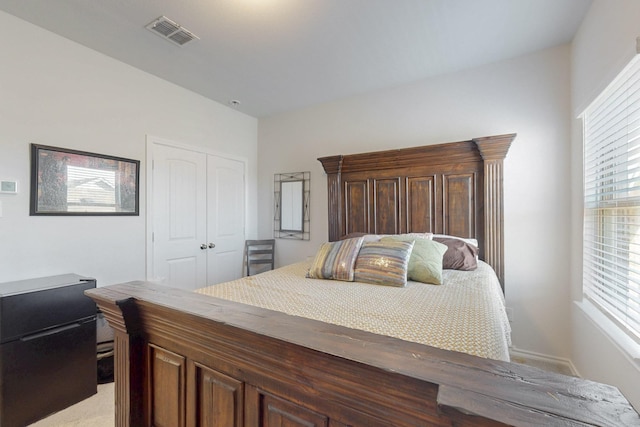 bedroom with visible vents, a closet, and light carpet