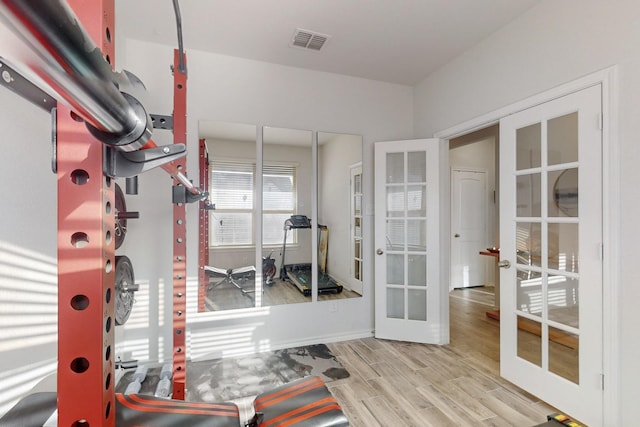 workout room with wood finished floors, french doors, and visible vents