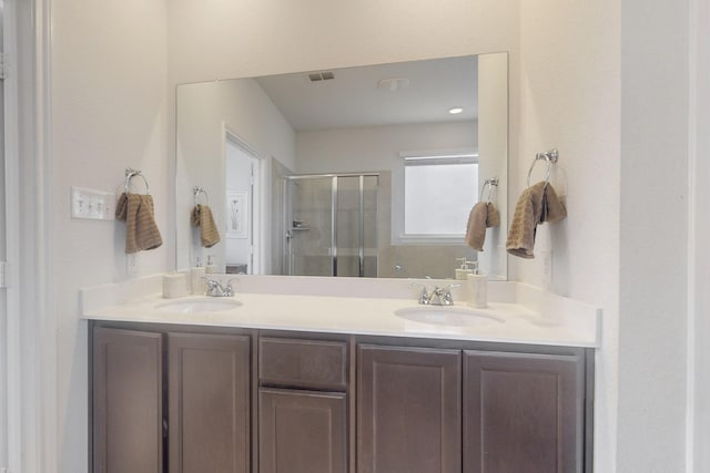 full bathroom with double vanity, visible vents, a stall shower, and a sink