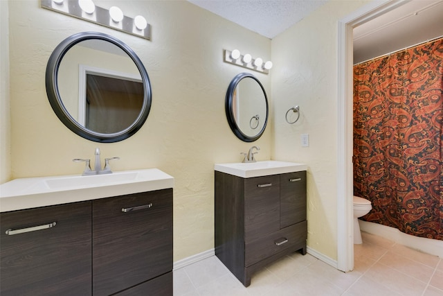 full bath with a sink, a textured ceiling, two vanities, and tile patterned flooring