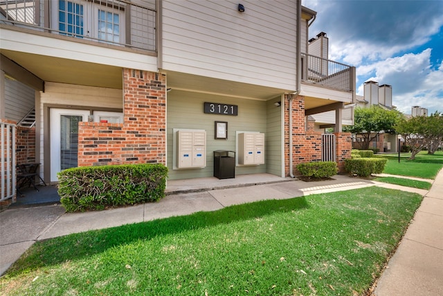 doorway to property featuring a yard and brick siding