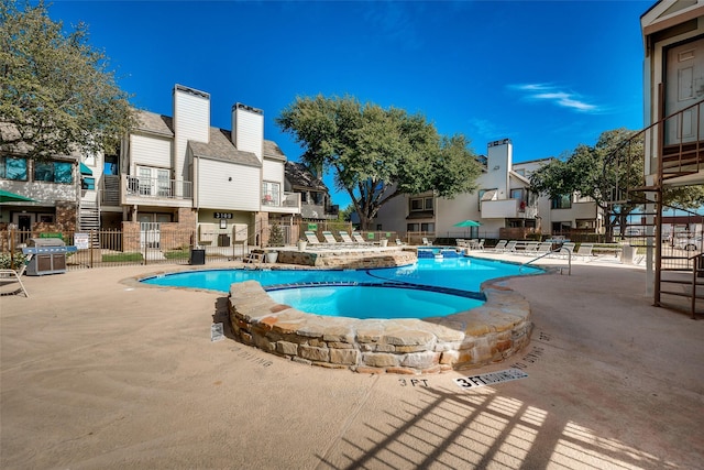 view of pool with a patio, a pool with connected hot tub, and a grill