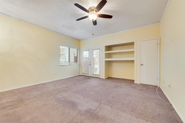 spare room with baseboards, a textured ceiling, crown molding, and carpet