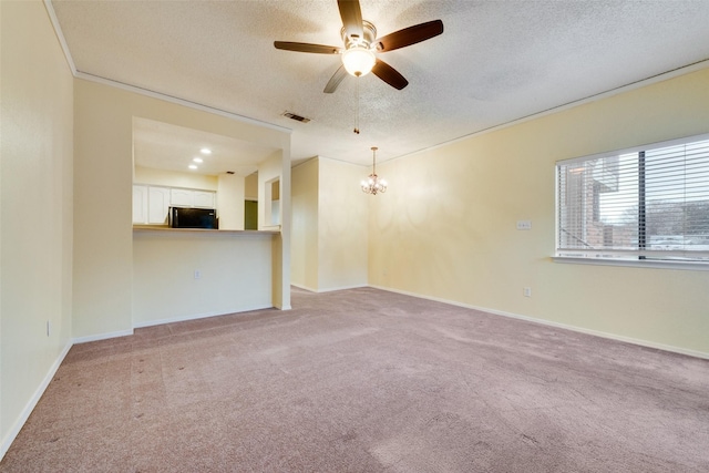 carpeted empty room featuring visible vents, ceiling fan with notable chandelier, a textured ceiling, and baseboards