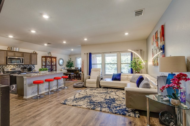 living area featuring recessed lighting, wood finished floors, and visible vents