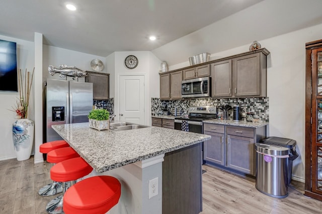 kitchen featuring a sink, light wood-type flooring, tasteful backsplash, and appliances with stainless steel finishes