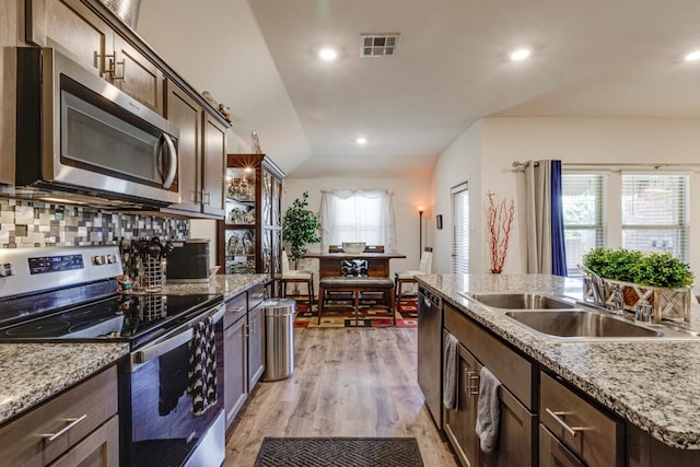 kitchen with visible vents, a sink, stainless steel appliances, dark brown cabinetry, and light wood-type flooring