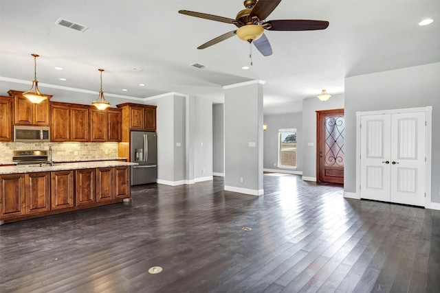 kitchen with visible vents, tasteful backsplash, appliances with stainless steel finishes, brown cabinetry, and dark wood-style flooring