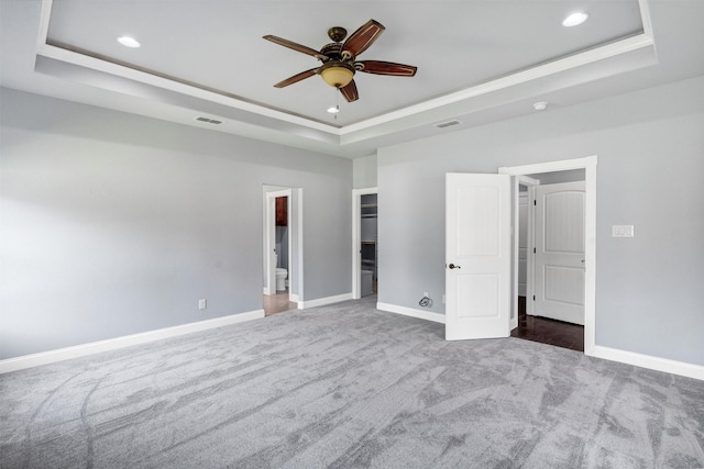 unfurnished bedroom featuring visible vents, a raised ceiling, carpet, and baseboards