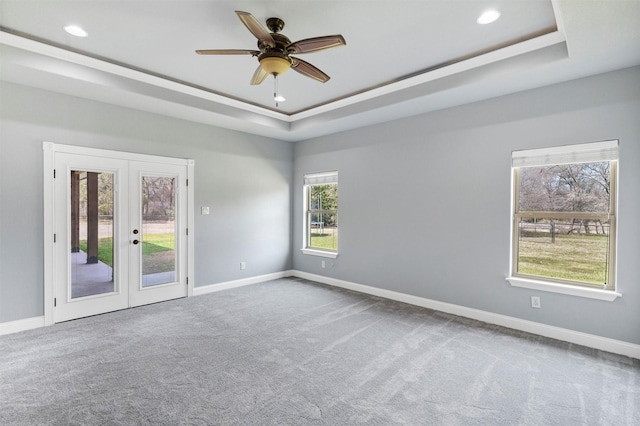 carpeted empty room with a tray ceiling and baseboards