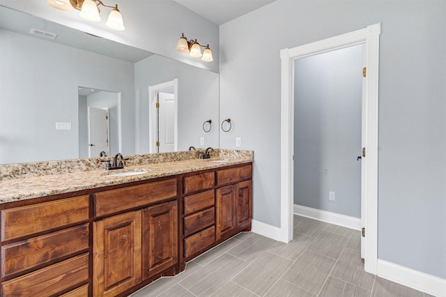 full bath featuring double vanity, visible vents, baseboards, and a sink