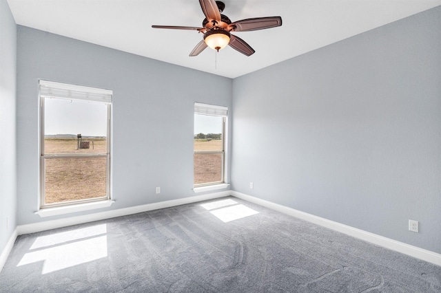 empty room with carpet flooring, ceiling fan, and baseboards