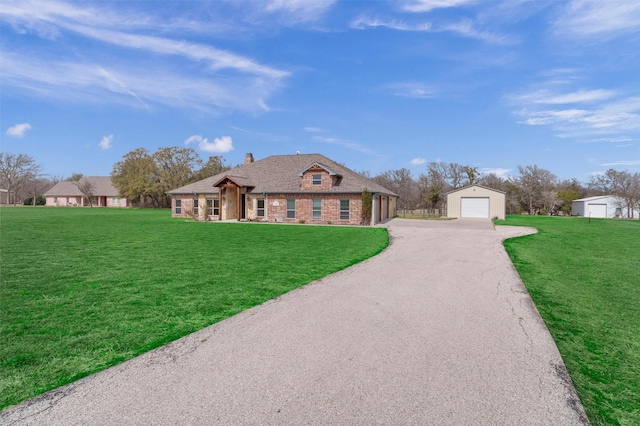 view of front facade featuring a front lawn, aphalt driveway, an outdoor structure, a garage, and brick siding