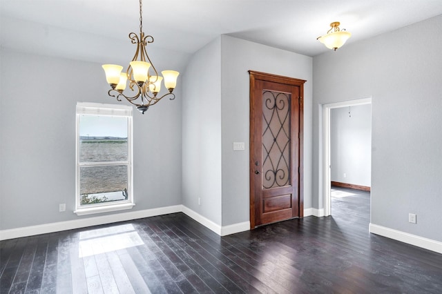 foyer featuring dark wood-style floors, a notable chandelier, and baseboards