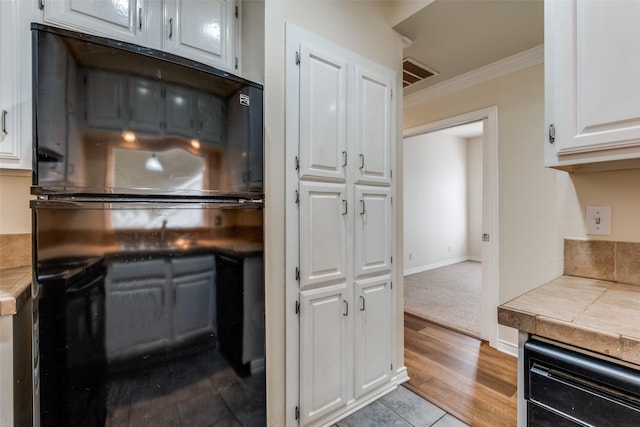 4034 Rawlins St Unit 102, Dallas, TX 75219 - kitchen with white cabinets, tile counters, ornamental molding, and dishwasher