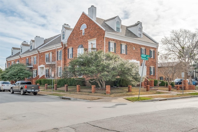 4034 Rawlins St Unit 102, Dallas, TX 75219 - view of front of home with brick siding, a chimney, and a fenced front yard
