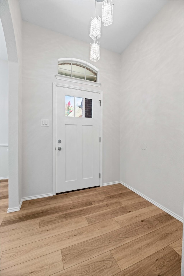 entrance foyer featuring baseboards, light wood-type flooring, and a chandelier