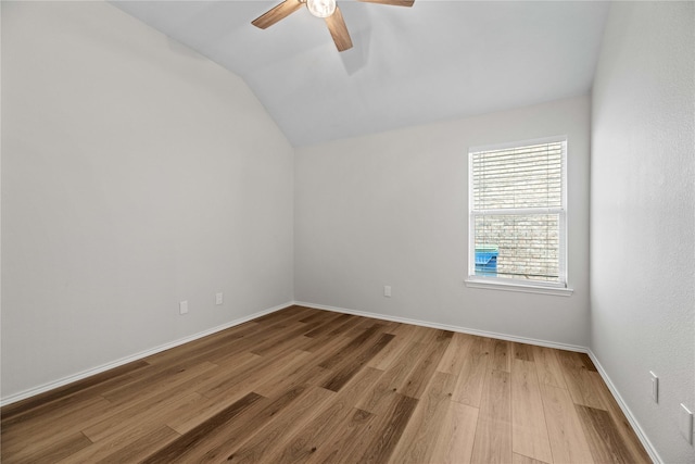 empty room with lofted ceiling, wood finished floors, baseboards, and ceiling fan