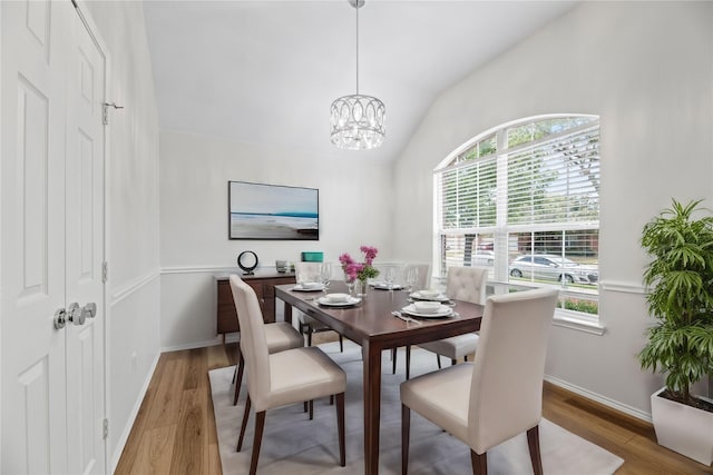 dining room with lofted ceiling, a notable chandelier, wood finished floors, and baseboards