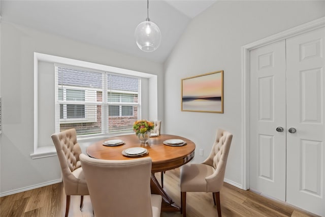 dining space with vaulted ceiling, wood finished floors, and baseboards