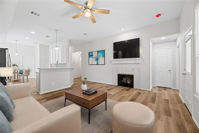 living area featuring light wood-type flooring, visible vents, recessed lighting, and a fireplace