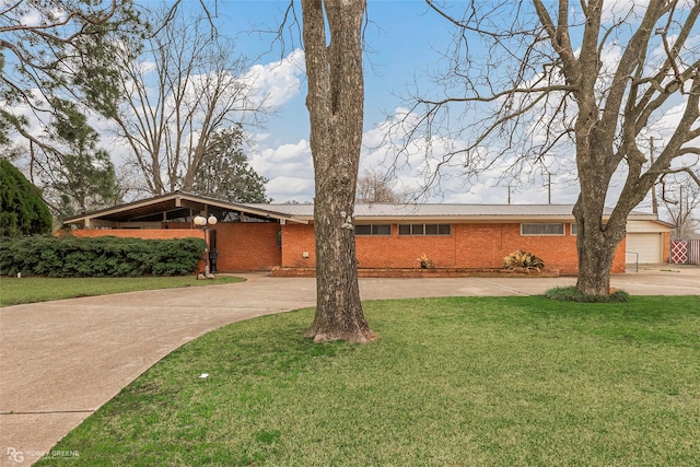 view of front facade with brick siding, concrete driveway, a front lawn, and metal roof