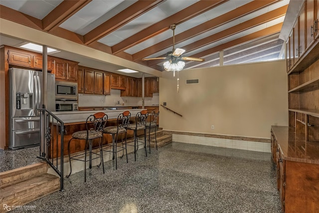 kitchen featuring visible vents, baseboards, brown cabinets, a kitchen breakfast bar, and appliances with stainless steel finishes