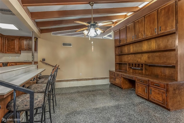 interior space featuring visible vents, baseboards, ceiling fan, beam ceiling, and built in desk