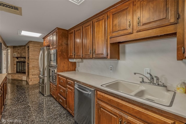 kitchen featuring visible vents, granite finish floor, a fireplace, a sink, and appliances with stainless steel finishes