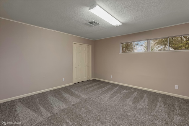 spare room with visible vents, dark carpet, a textured ceiling, and baseboards