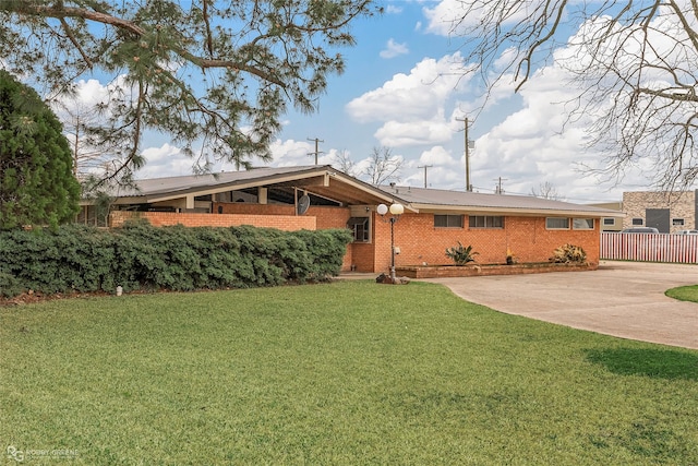 view of front of house featuring brick siding, concrete driveway, a front yard, and fence