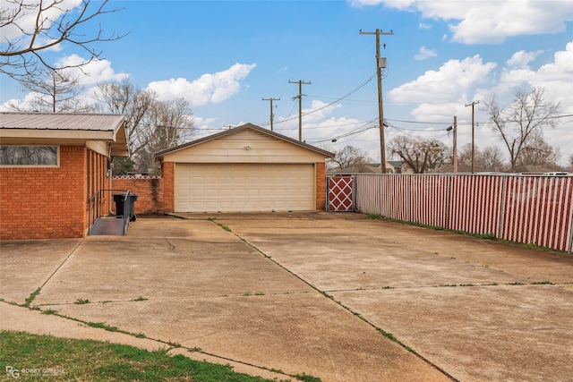 view of side of home with an outbuilding, a detached garage, brick siding, and fence