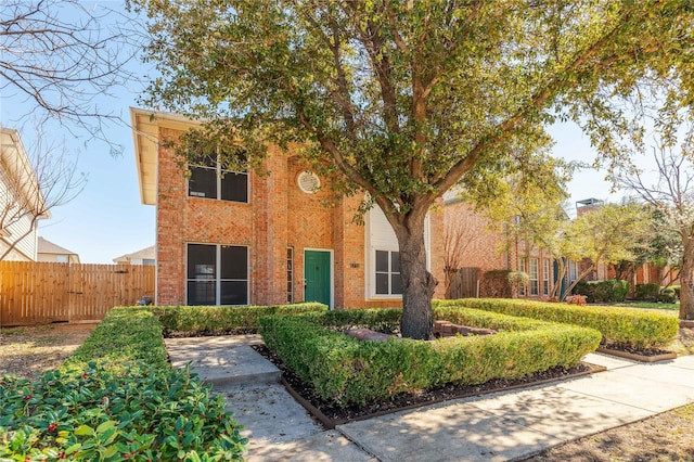 view of front facade with brick siding and fence